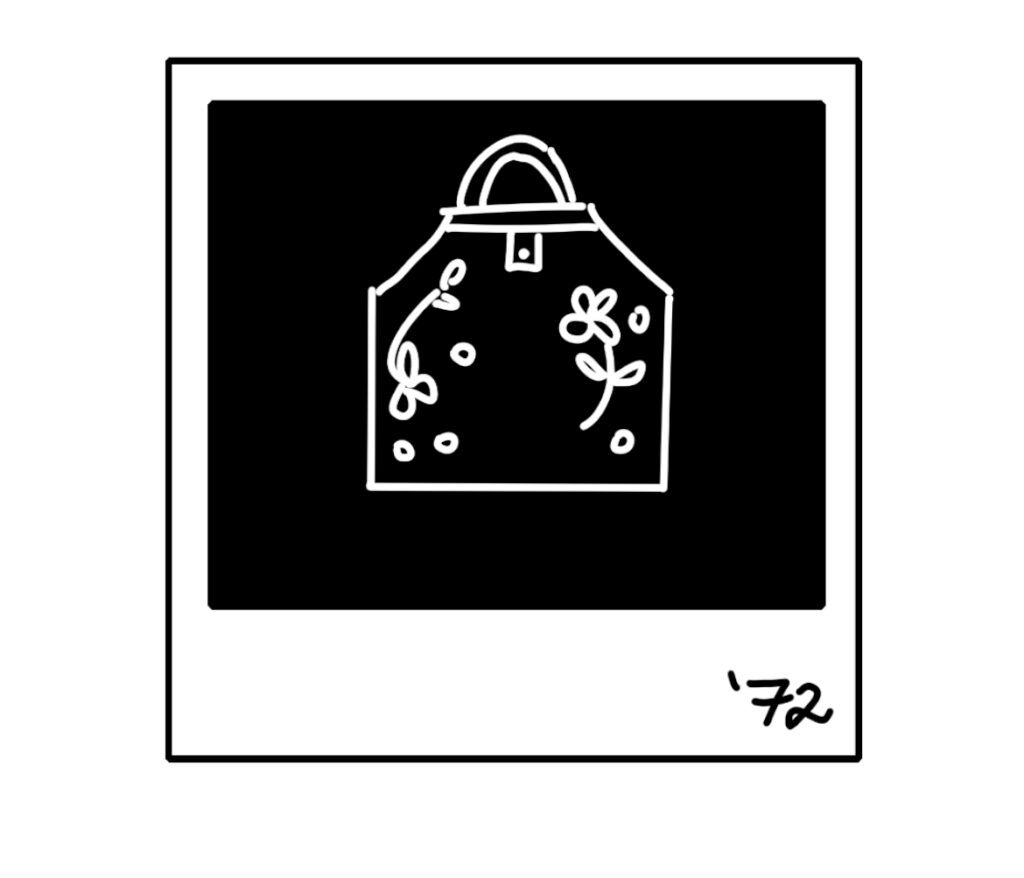 In black and white. An illustrations of a Polaroid of an decorated apron with "'72'" written in the bottom right corner.